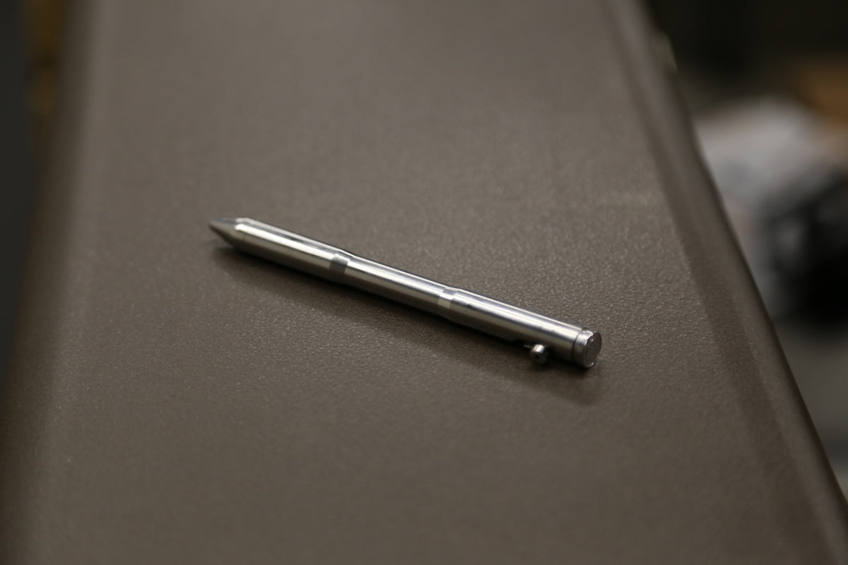 Reverse angle of the Drift titanium pen resting on a workshop tray.