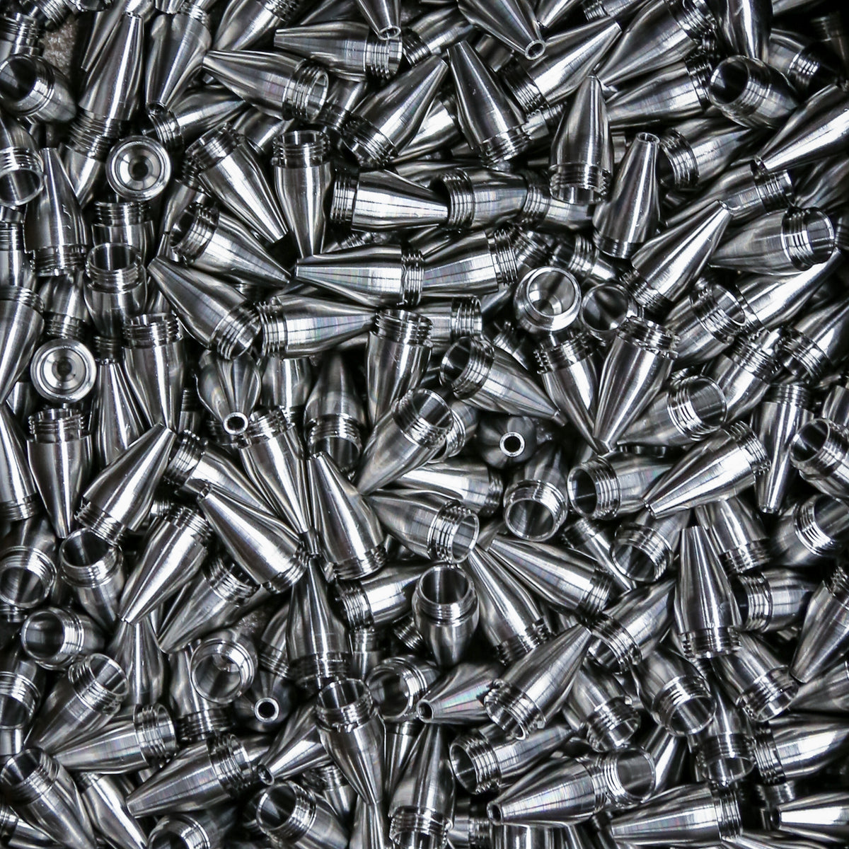 A batch of machined metal pen tips with threaded bases.